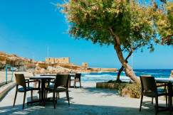 An illustrative photo of brown wooden table and chairs on a beach during daytime.